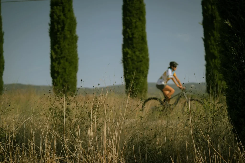 Ciclista gravel tra i cipressi della campagna toscana
